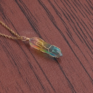 Detailed view of wire-wrapped rainbow crystal column pendant on a golden chain necklace