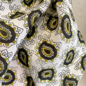 Close-up of white paisley pattern scarf fabric with yellow and black weaving details