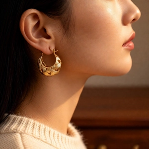 Detail of 18k gold plated hollow U-shaped woven texture hoop earring on a model