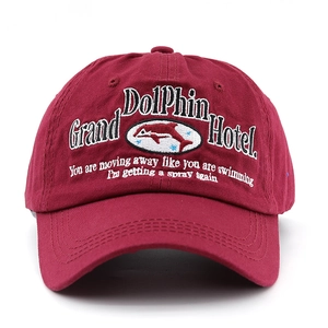 Close-up of the detailed Grand Dolphin Hotel embroidery on this wine red washed cotton cap
