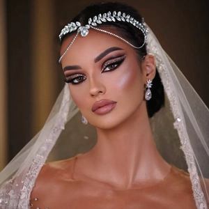 Detail of bridal forehead chain and earrings with radiant rhinestones on a model