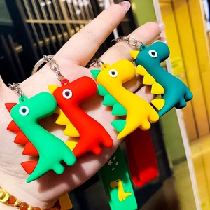Close-up of colorful cartoon dinosaur keychains in green, red, and yellow PVC material