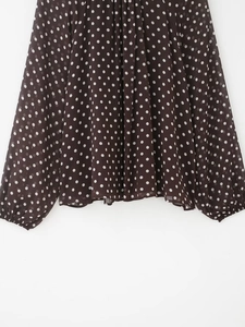 Dettaglio della trama plissettata e del motivo a pois bianchi sulle maniche lunghe in chiffon