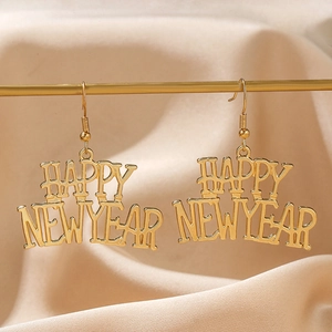 Dettaglio di orecchini dorati festivi con scritta Happy New Year su sfondo di seta