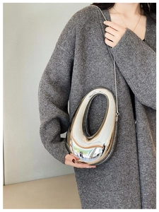 Close-up of polished silver acrylic sculptural oval clutch with elegant chain strap