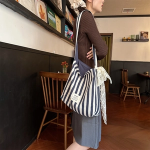 Blue and white striped canvas tote bag detail with side lace ribbon and woven label