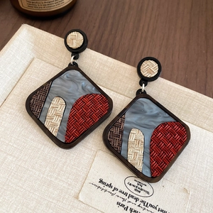 Close-up of vintage geometric acrylic earrings with woven fabric and marble resin texture
