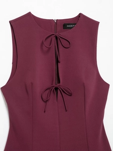 Detail of burgundy sleeveless dress featuring bow ties and hidden collar zipper