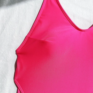 Detailed close-up of the bright pink bikini neckline and straps on linen background
