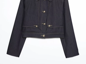 Détail des surpiqûres contrastées et boutons dorés sur veste courte en jean