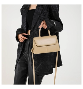 Chic beige crossbody bag with top handle and leather texture shown on a fashion model