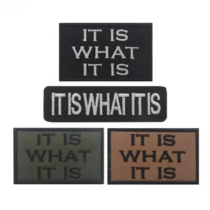Detail of embroidered It Is What It Is tactical morale patches in black green and tan