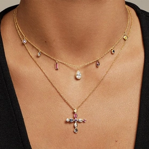 Detail of layered gold S925 silver necklace with cross pendant and colorful zircons
