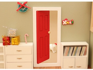 Macro shot of miniature red dollhouse door with white frame and tiny bear Christmas decor