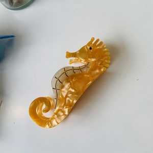 Unique seahorse shaped acetate hair claw clip in amber yellow with pearlescent finish