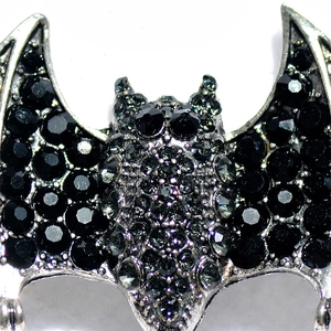 Macro view of gothic bat brooch featuring crystal pavé setting on antique silver metal