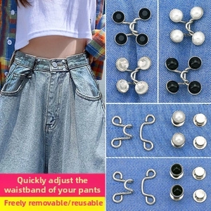 Detail showing various waist adjustment pins including pearl and black gem styles on denim