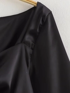 Detail der glänzenden schwarzen Satin-Langarm-Top-Stofftextur und Ausschnitt-Finish