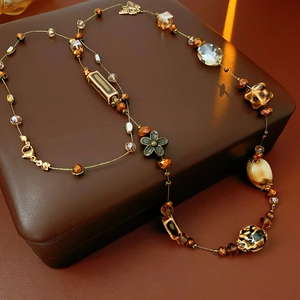 Dettaglio di collana multistrato bohémien con ciondoli a farfalla su scatola in pelle