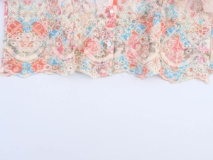Detailed macro view of floral embroidery and scalloped lace hem on short sleeve blouse