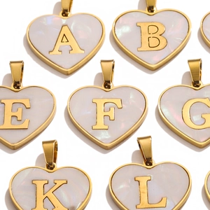 Macro shot of gold heart-shaped pendants with white pearlescent inlay and gold letters