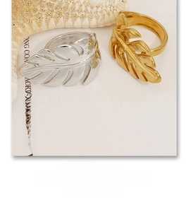 Macro shot of gold and silver leaf-shaped rings with fine vein textures and metallic luster
