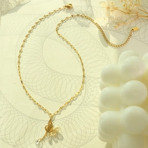Elegant 18K gold-plated butterfly pendant necklace with zircon tassels on a textured surface