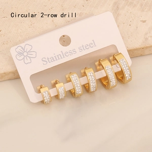 Detail of three pairs of golden stainless steel hoop earrings with double-row crystals