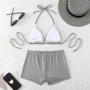 Flat lay of black and white checkered bikini set with high-waisted shorts and straw hat