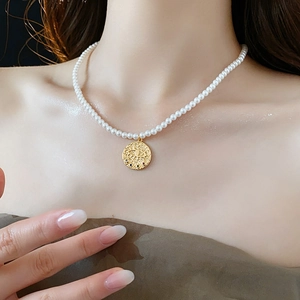 Gros plan d'un collier de perles en or avec pendentif pièce totem œil sur le cou d'une femme
