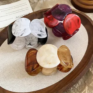 Acrylic marble patterned round link bracelets in black, purple, and amber on a wooden tray