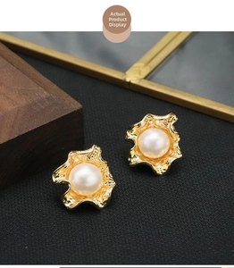 Detail of 18k gold plated vintage pearl earrings with textured metal on black fabric