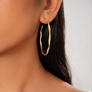 Close-up of elegant gold twisted circular earrings worn on a model for a chic look