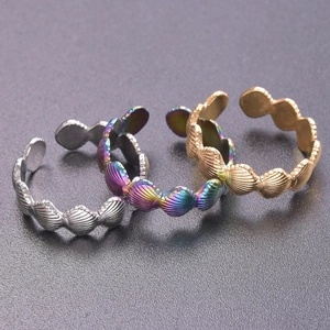 Macro shot of three scallop-style adjustable rings in silver, gold, and rainbow finishes