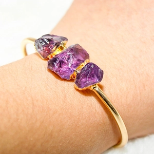 Adjustable gold plated cuff bracelet featuring three natural raw purple amethyst stones