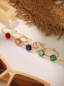 Macro detail of faceted colorful glass gems set in golden open bangles for women