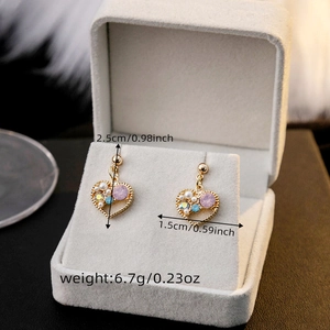 Detail view of heart-shaped gold earrings with purple crystals, pearls and size dimensions