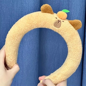 Detail of plush Capybara headband with cute orange ornament and embroidered features