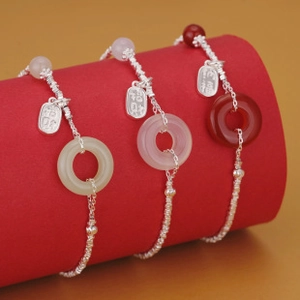 Detailed macro view of S925 silver bracelets with colorful jade pendants and charms