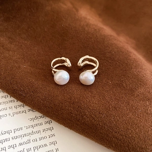 Detailed view of French vintage gold pearl ear cuffs on brown suede fabric background