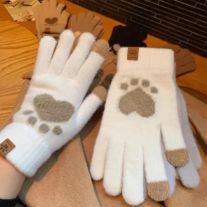 Detail of cream knitted touch screen gloves with heart pattern and leather cat paw label