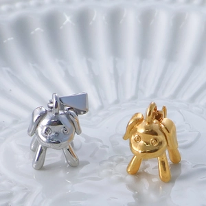 Detailed view of dog-shaped pendants in gold and silver finish on ceramic tray