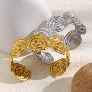 Detail of spiral geometric open bracelets in gold and silver polished stainless steel finish