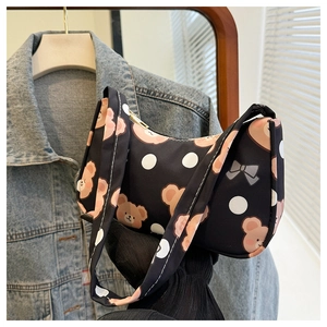 Detail of black canvas shoulder bag featuring brown bear pattern and white polka dots