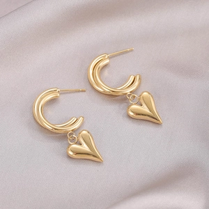 Orecchini vintage a cuore dorati con ganci a C su sfondo di raso elegante e lussuoso