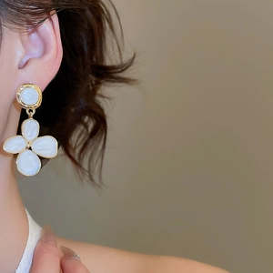 Boucles d'oreilles fleurs dorées avec émail blanc sur mannequin au style vintage chic