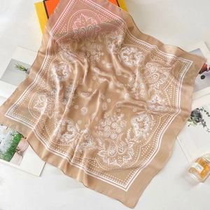 Detail of silk satin square scarf with paisley pattern next to premium packaging box