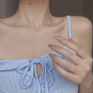 Close-up of S925 sterling silver heart necklace with iridescent stone on a model's collarbone