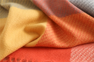 Close-up of soft plaid scarf fabric showing yellow red and grey knit texture with tassels