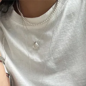 Detail of layered S925 silver shell pendant necklaces with snake and bead chains